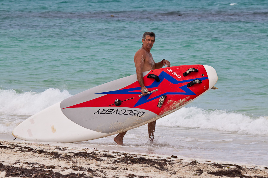 Surfer on Hodges Bay beach, Antigua, Antigua and Barbuda, Leeward Islands, West Indies, Caribbean. Сёрфер на пляже Ходжес-бэй, остров Антигуа, Антигуа и Барбуда, Карибы.