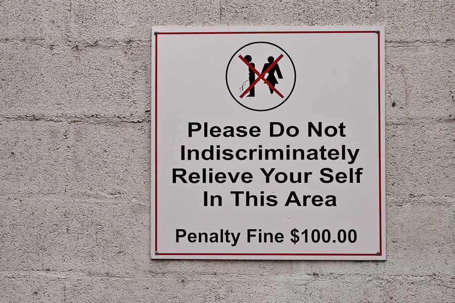 Please do not indiscriminately relieve your self in this area, penalty fine $100.00 sign, St. John's city, Antigua island, Antigua and Barbuda, Caribbean. Safety First, Keep site tidy sign. Знак о штрафе в $100 на улице города Сент-Джонса, остров Антигуа, Антигуа и Барбуда, Карибский бассейн.