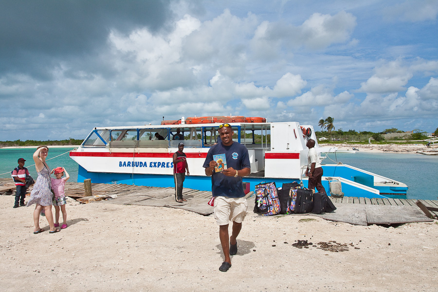 Катамаран Barbuda Express в порту острова Барбуда, Антигуа и Барбуда. Пассажиры, чемоданы и член команды. The Barbuda Express catamaran in the port of Barbuda, Antigua and Barbuda, Caribbean. Passengers, suitcases and a crew member.
