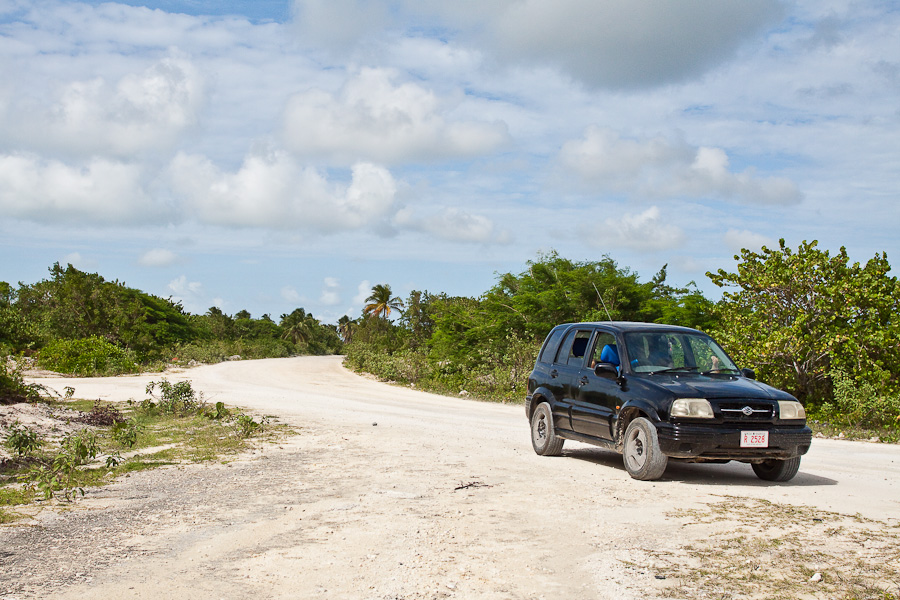 Грунтовая дорога вокруг острова Барбуда и чёрная машина, Антигуа и Барбуда. A dirt road around the island of Barbuda, a black 4x4 car, Antigua and Barbuda, Caribbean. R2528 plate