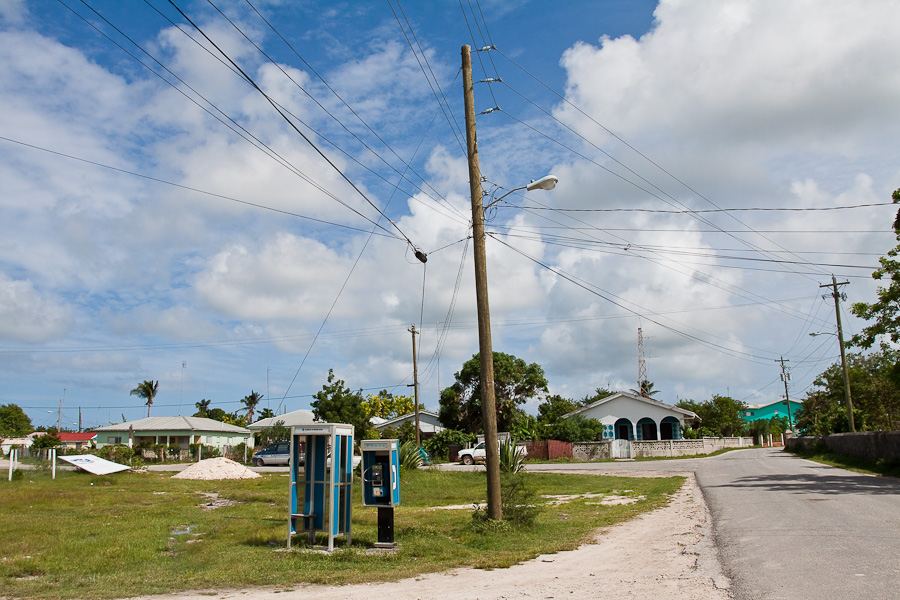 Overhead wires, phone booths, on a streets of Codrington town, Barbuda, Antigua and Barbuda, Caribbean. Улица города Кодрингтон, провода на столбах, телефонная будка, телефон-автомат, остров Барбуда, Антигуа и Барбуда