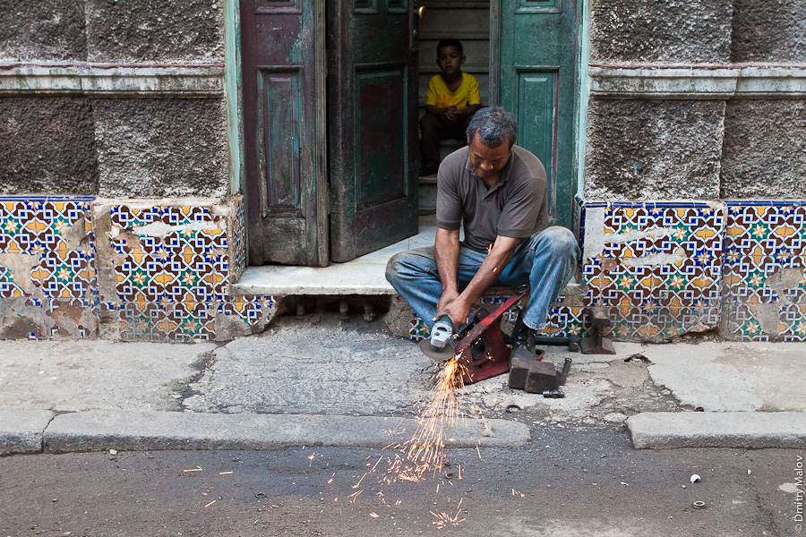 Мужчина использует болгарку на улице Гаваны, Куба. A man uses a grinder on a street in Havana, Cuba.