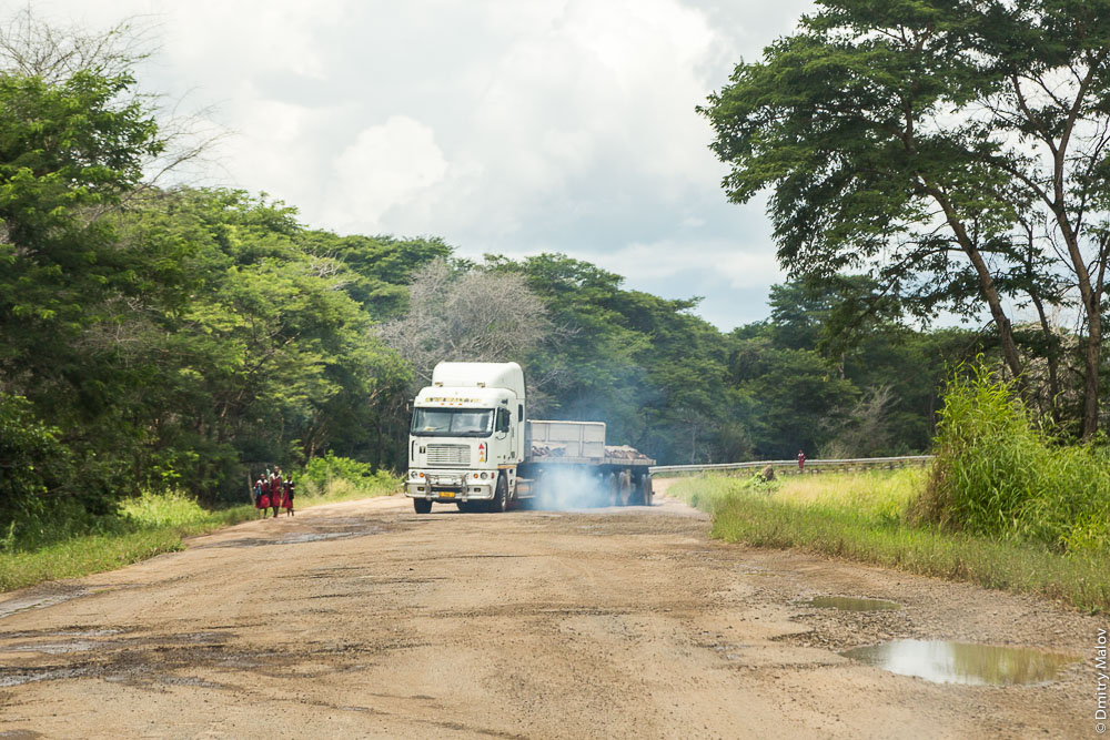 Potholes and smoking african truck on M10 road Zambia, Barotseland, Sesheke town - Livingstone, Africa. Трасса Сешеке-Ливингстон, Замбия, Баротселенд, Африка, вся в ямах, дымящаяся фура