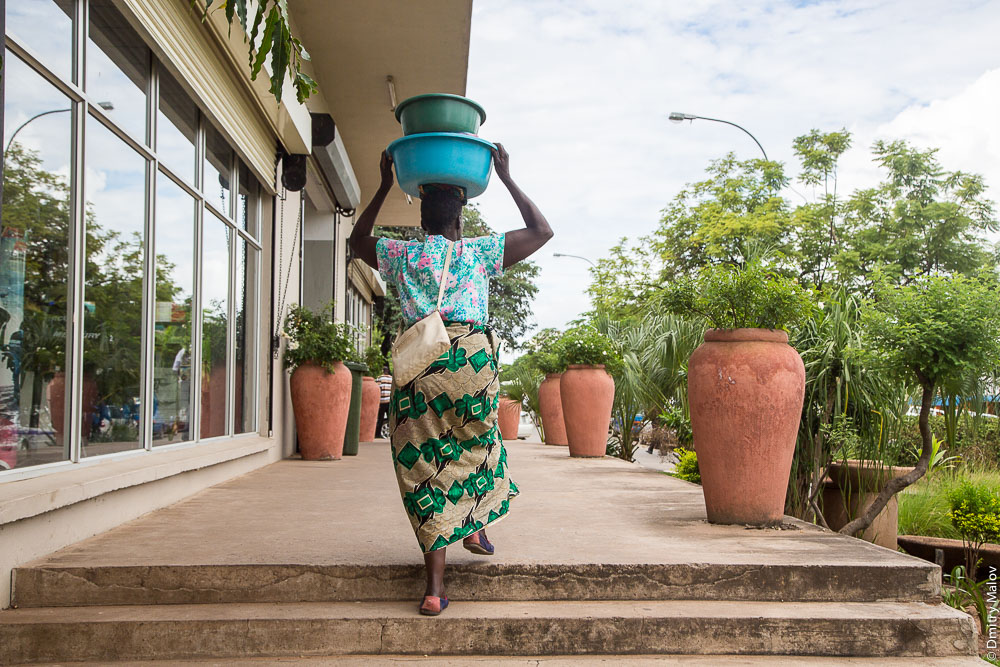 Woman with a load on their heads. Livingstone downtown, Zambia, city centre, on the main street. Город Ливингстон, Замбия. Центр, женщина с тазами на голове на центральной улице.