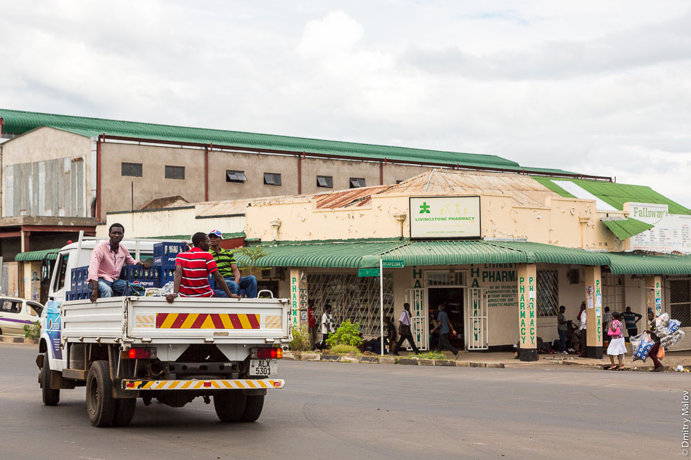 Город Ливингстон, Замбия. Центр, на главной улице, пассажиры в грузовике. Livingstone city downtown, Zambia, town centre, on the main street. People on truck