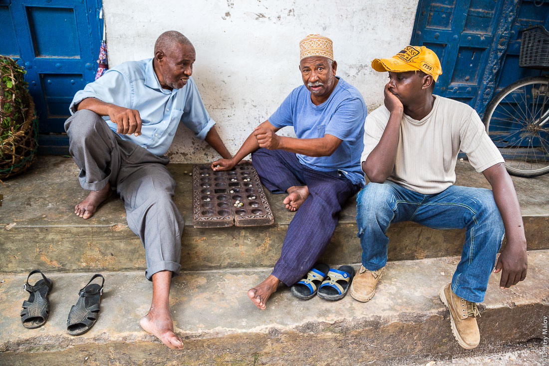 Игроки в манкалу (месные жители играют в зёрна). Каменный город, старая часть Занзибар-сити, остров Унгуджа, Танзания. Locals are playing Mancala. Stone Town, old town of Zanzibar City, Unguja island, Tanzania