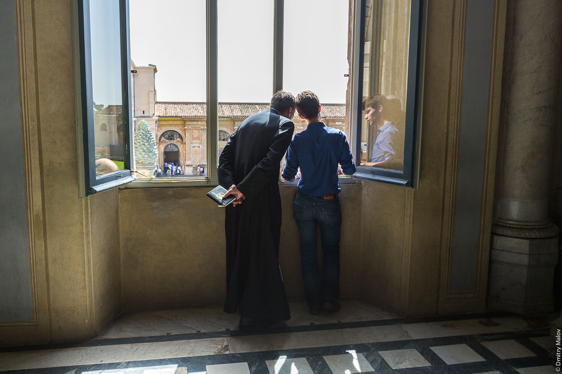 Пастор и юноша смотрят из окна во внутренний двор музеев Ватикана. A pastor and a young man look out the window into the inner courtyard of the Vatican Museums.