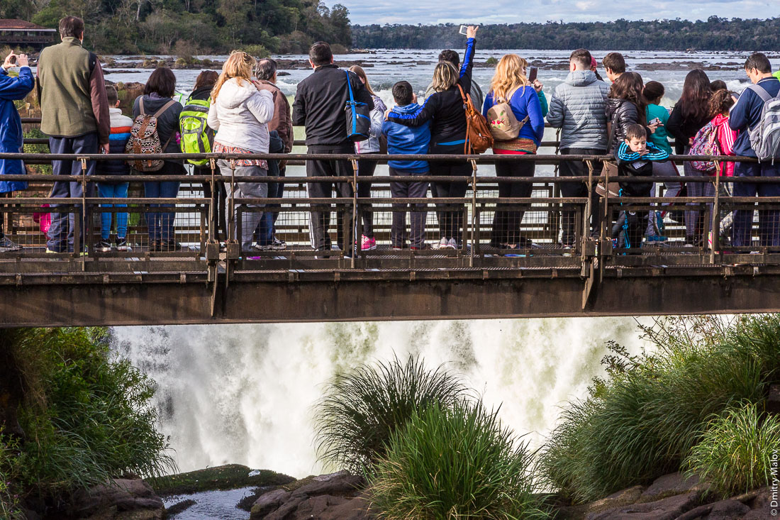 Туристы смотрят на водопад Глотка дьявола, водопад Игуасу, Бразилия, Аргентина. Tourists at canopy boardwalk at Garganta del Diablo. Devil's Throat, Iguazu Falls, Brazil, Argentina. 