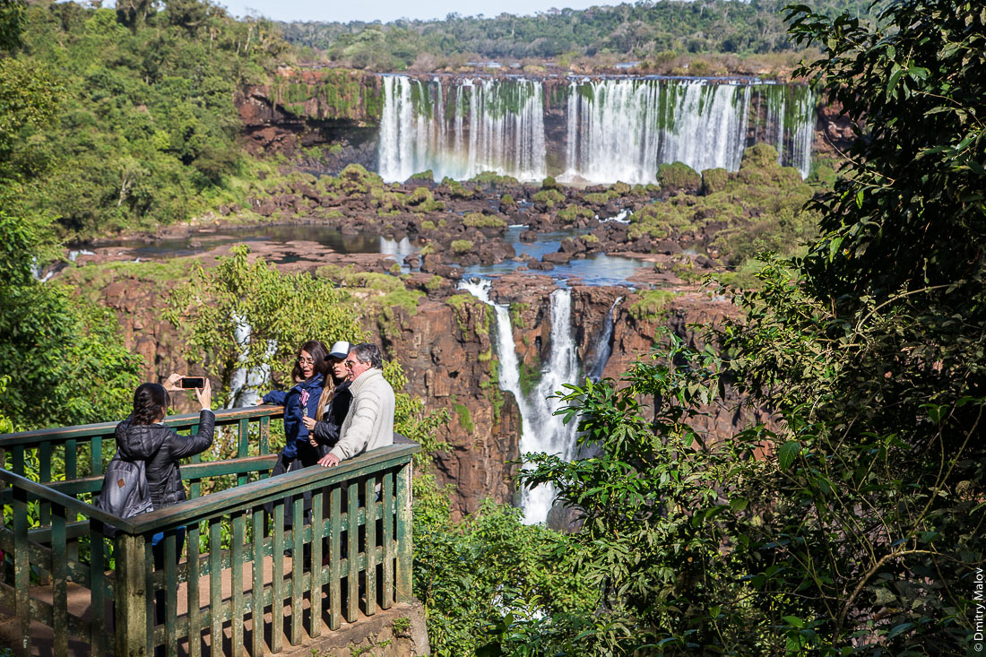 Туристы делают селфи. Вид с бразильской стороны на аргентинскую часть водопадов Игуасу. Tourists capturing photos. A view from the Brazilian side to the Argentine part of Iguazu waterfalls.