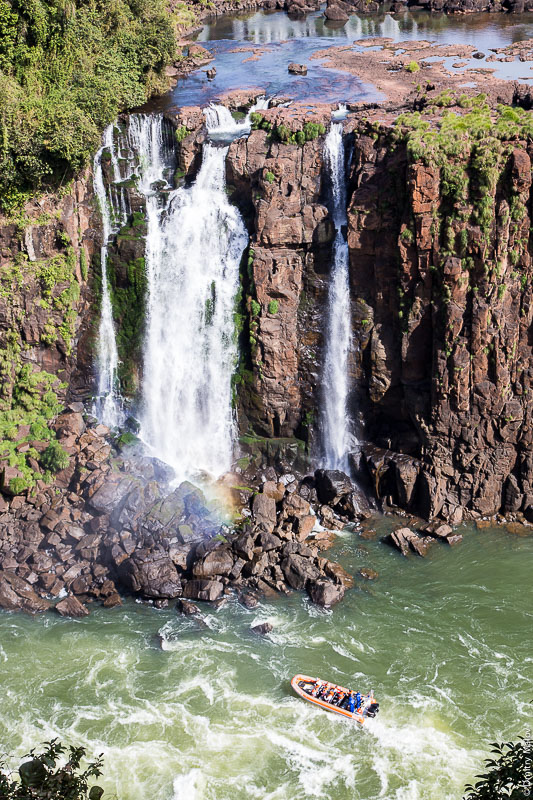 Лодочный круиз под водопадом. Вид с бразильской стороны на аргентинскую часть водопадов Игуасу. Tourists on a boat ride. A view from the Brazilian side to the Argentine part of Iguazu waterfalls.