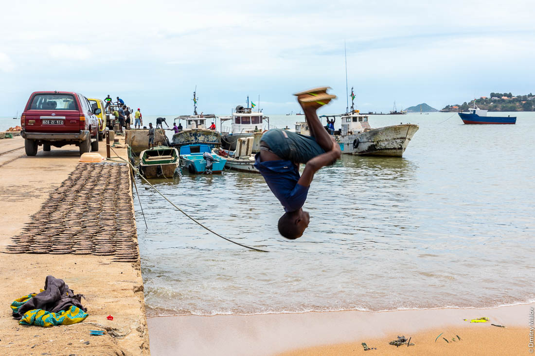 Мальчик-африканец делает сальто. На набережной, город Сан-Томе, столицы Сан-Томе и Принсипи
